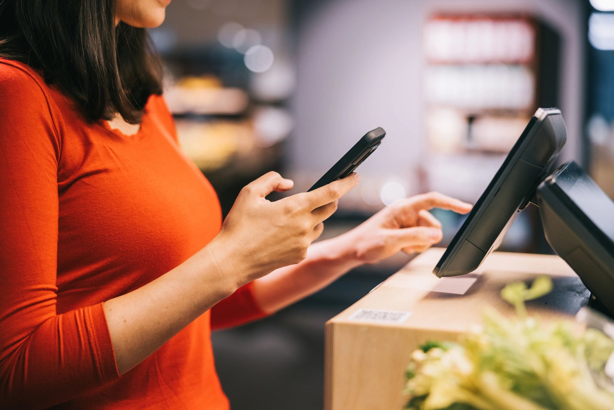 Woman using her smartphone at a grocery self-service terminal