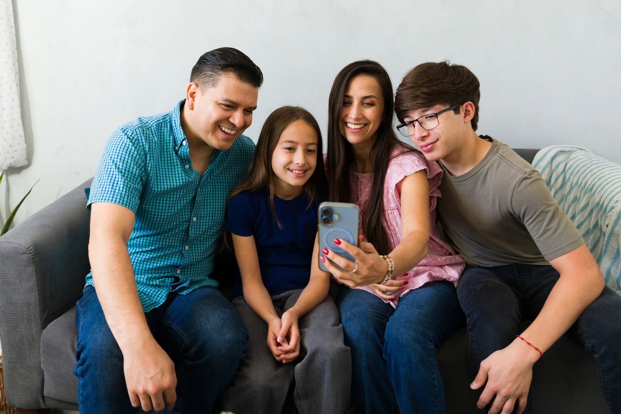 Family at home using a smartphone together on the sofa